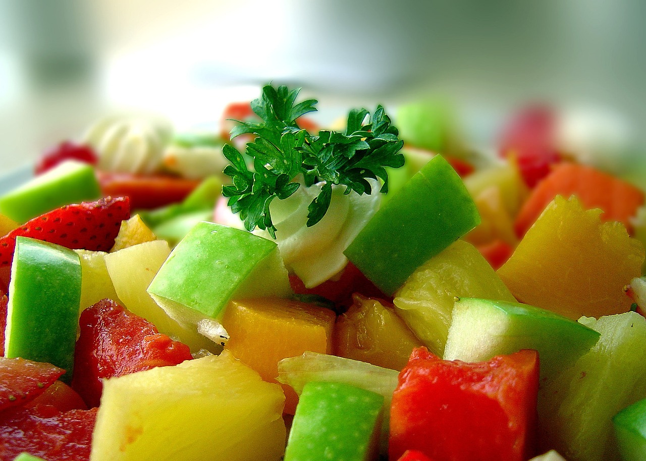 Salade de fruits frais et colorée garnie de persil, représentant un repas sain pour les enfants au camp.